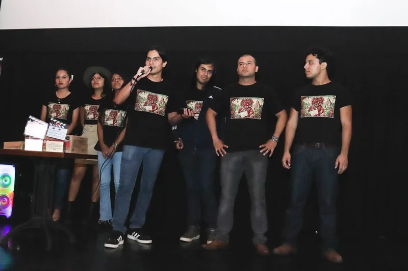 Participantes del festival con reconocimientos frente a la pantalla